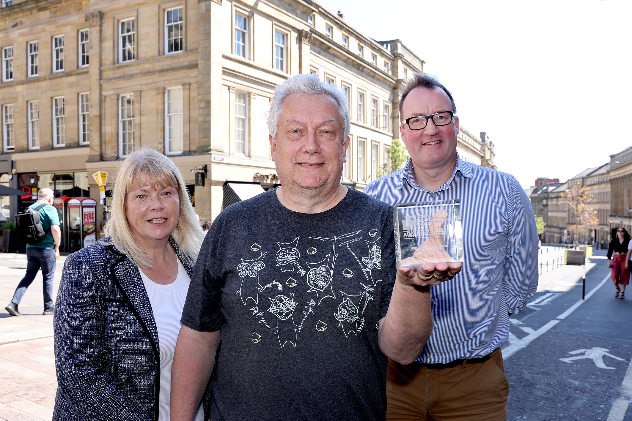 John receiving his award from Tim Bailey and Catriona Lingwood on a sunny Grey Street in Newcastle.